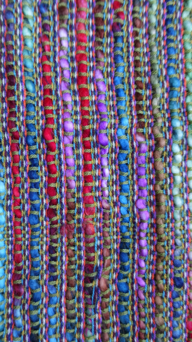 Earthy toned hands and looms woven colourful scarf – corner detail