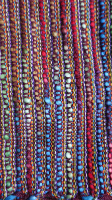 Colourful hands and looms colourful winter scarf – close-up of the embellishment