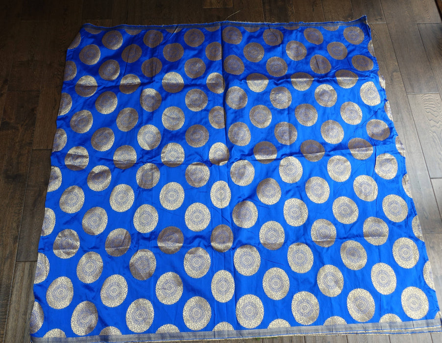 A royal blue fabric, It features a repeating pattern of large, metallic silver circular medallions with intricate gold and silver woven details.